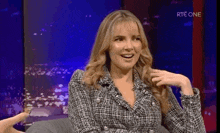 a woman in a plaid jacket is sitting in a chair on a television show .
