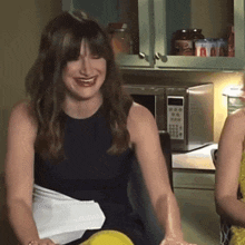 a woman is smiling in front of a microwave that says ' aa ' on the screen