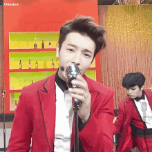 a man in a red jacket is singing into a microphone .