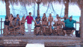 a group of people are sitting on a dock with the words in diretta dall honduras la palapa esterna on the bottom