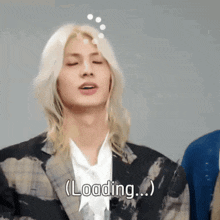 a man with long blonde hair says loading on his face