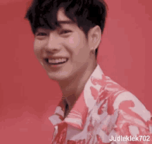 a close up of a young man wearing a pink and white shirt and smiling .