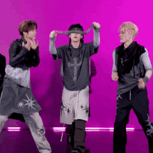 three men are dancing in front of a pink background