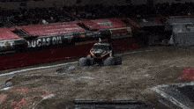 a monster truck is driving through a muddy field with a lucas oil banner in the background