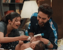 a man and woman are feeding a baby with a bottle