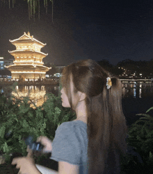 a woman stands in front of a lit up building