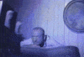 a man laying on a couch in a dark room with a picture on the wall behind him