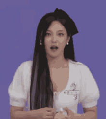 a woman with long black hair is wearing a white top and a black beret .