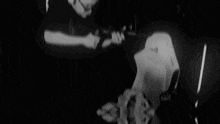 a black and white photo of a man holding a gun in a chair .