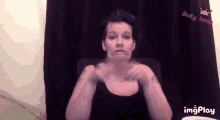 a woman is making a funny face in front of a black curtain with a betty boop logo in the corner