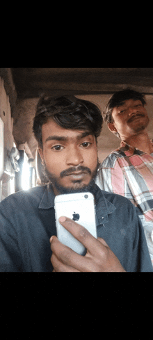 a man with a beard is taking a picture of himself with an iphone