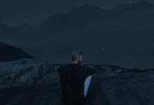 a man in a black shirt sits on a rock at night