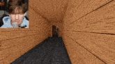 a man in a blue hoodie is talking into a microphone in a wooden hallway