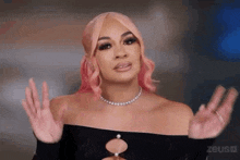 a woman with pink hair is wearing a necklace and a black top .