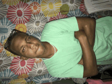 a man in a green shirt is laying on a colorful floral blanket