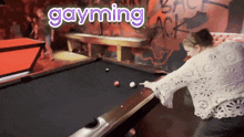 a woman is playing pool with the words gayming above her