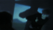 a blurry image of a person in a dark room with a picture frame in the background