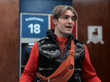 a man wearing a black vest and a red shirt with the number 18 on it