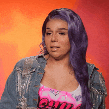 a woman with purple hair is wearing a denim jacket and a pink tank top that says ' oui ' on it