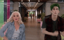 a man with green hair is standing next to a woman in a hallway ..
