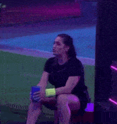 a woman is sitting on a bench with her arms in the air and holding a blue cup .