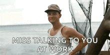 a man in a tank top and hat is standing on a boat in the ocean with the words `` miss talking to you at work '' .