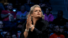 a woman praying in front of a crowd with the aew logo on the bottom