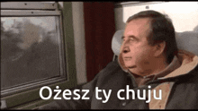 a man sitting on a train looking out the window with the words ozesz ty chuju written on the bottom