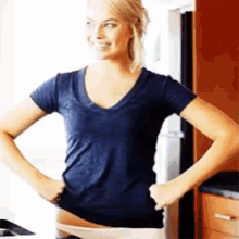 a woman in a blue t-shirt is taking off her underwear