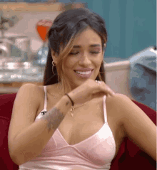 a woman in a pink bra is sitting on a red couch smiling