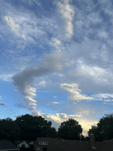 a house with a chimney on the roof and a blue sky with clouds
