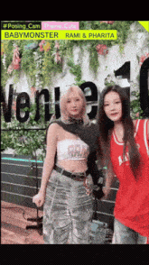 two girls pose for a picture in front of a sign that says " babymonster rami & pharifa "
