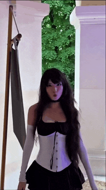 a woman with long black hair is wearing a white corset and a black dress .