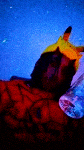 a person wearing a pikachu hat is laying down with a bottle of water next to them