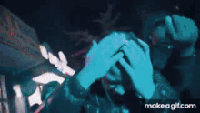 a person with dreadlocks is covering their face with their hands in a dark room .
