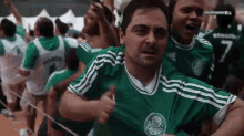 a man in a green palmeiras jersey is surrounded by other fans