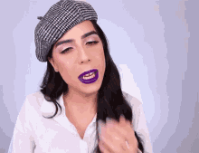 a woman wearing a beret and purple lipstick is making a face .