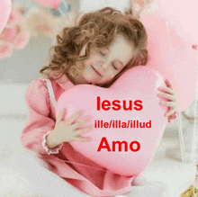 a little girl holding a pink heart with the words jesus ille/illa/illud amo on it
