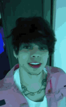 a young man wearing a pink jacket and a white shirt has a tattoo on his neck