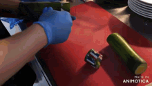 a person wearing blue gloves is cutting a cucumber on a red cutting board made in animatica