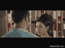 a man and a woman are looking into each other 's eyes in a room .
