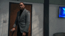a man in a suit is holding a gun and walking through a doorway .