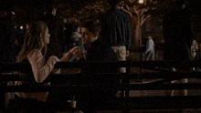 a man and a woman are sitting on a bench in a park at night