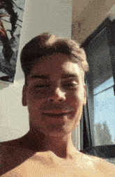 a young man without a shirt is smiling for the camera .