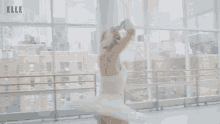 a ballerina is dancing in a dance studio with her arms outstretched .