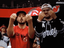 two men wearing jersey jerseys are cheering in a crowd