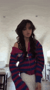 a young woman is wearing a striped sweater and a red and blue jacket .