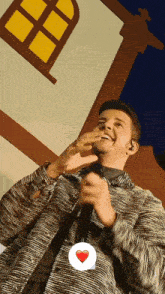 a man singing into a microphone with a heart in the corner