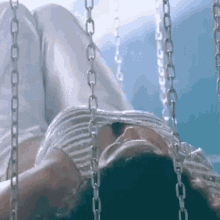 a woman laying on a swing with chains around her