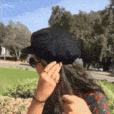 a woman is wearing a black hat and sunglasses .